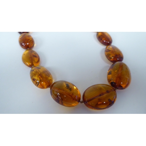 237 - An amber coloured graduated oval bead necklet, the dog-clip clasp stamped 925