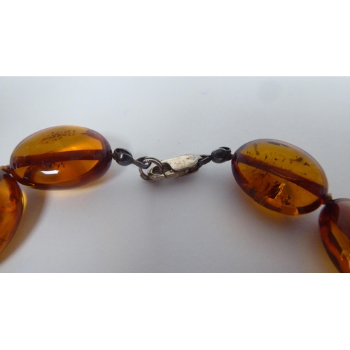 237 - An amber coloured graduated oval bead necklet, the dog-clip clasp stamped 925