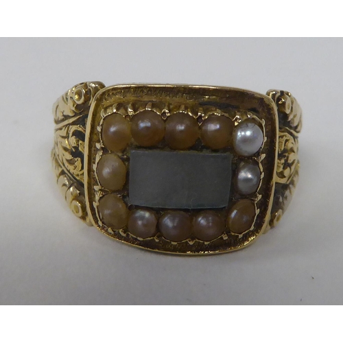 252 - An antique gold coloured metal mourning ring with an engraved shank, set with seed pearls 