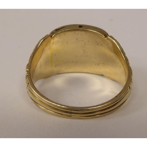 252 - An antique gold coloured metal mourning ring with an engraved shank, set with seed pearls 