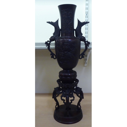 253 - A modern Japanese two-part bronze, twin handled, ornately cast vase, decorated in relief with grotes... 