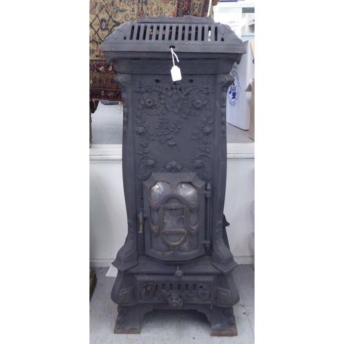 369 - An early 20thC cast iron wood burning stove, decorated in relief with flora, on a bracket plinth&nbs... 