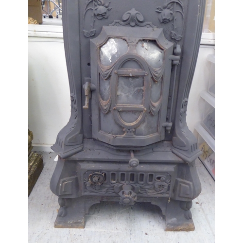 369 - An early 20thC cast iron wood burning stove, decorated in relief with flora, on a bracket plinth&nbs... 