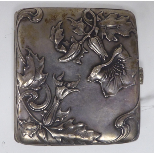 439 - An Art Nouveau silver coloured metal folding cigarette case, on a button clasp, decorated with cast ... 