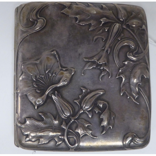 439 - An Art Nouveau silver coloured metal folding cigarette case, on a button clasp, decorated with cast ... 