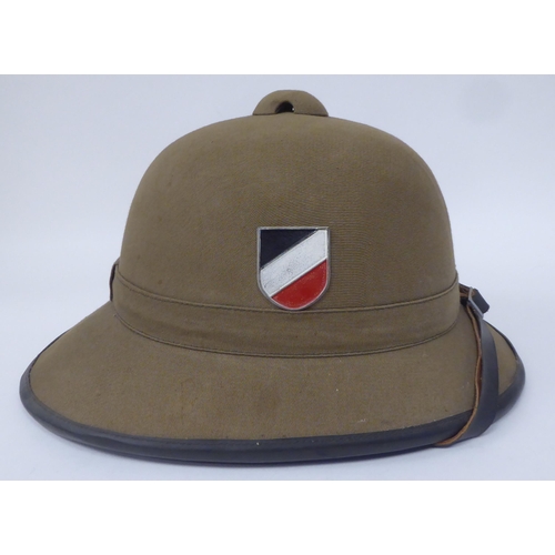 47 - A Royal Welsh Fusiliers, Hawkes & Co khaki coloured pith helmet and liner; a similar German helm... 