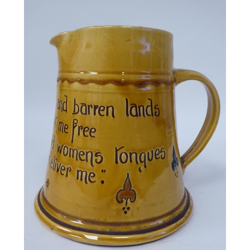 62 - A West Country yellow glazed pottery ale jug of tapered form, inscribed  'From rocks and Lands and B... 