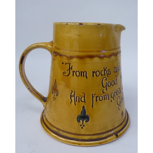 62 - A West Country yellow glazed pottery ale jug of tapered form, inscribed  'From rocks and Lands and B... 