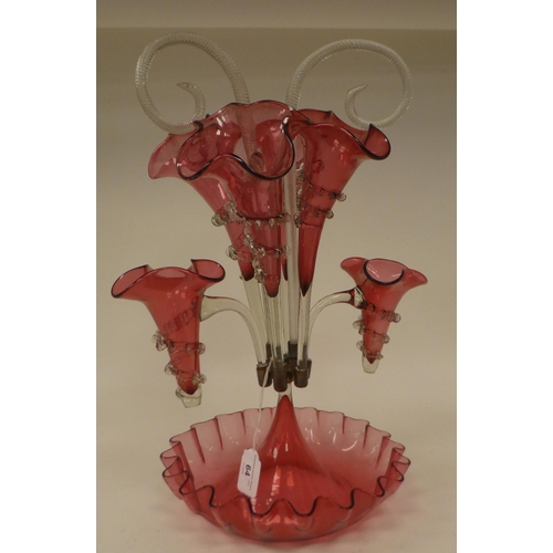 64 - An Edwardian Cranberry glass epergne with frilled borders, comprising a series of six trumpets and c... 