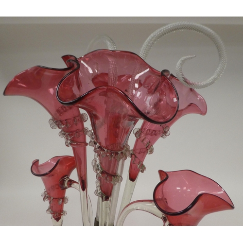 64 - An Edwardian Cranberry glass epergne with frilled borders, comprising a series of six trumpets and c... 