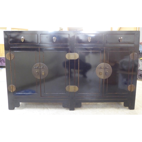 66 - A modern Japanese inspired black painted sideboard with four inline drawers, over four doors, raised... 