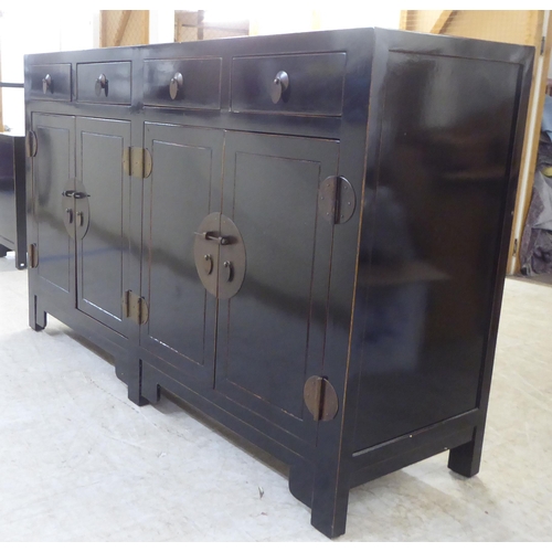 66 - A modern Japanese inspired black painted sideboard with four inline drawers, over four doors, raised... 