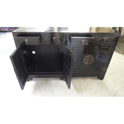 66 - A modern Japanese inspired black painted sideboard with four inline drawers, over four doors, raised... 