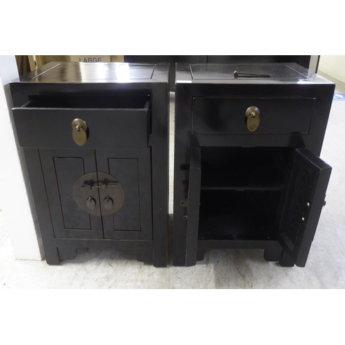 67 - A pair of modern Japanese inspired black painted bedside chests, each with a single drawer, over two... 