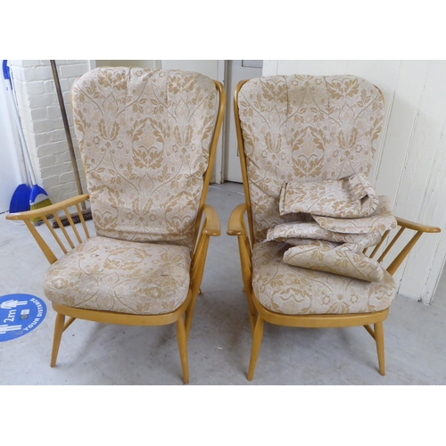 68 - A pair of Ercol high back blonde beech and elm framed, spindled open arm chairs with loose fabric co... 