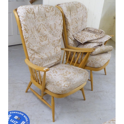 68 - A pair of Ercol high back blonde beech and elm framed, spindled open arm chairs with loose fabric co... 