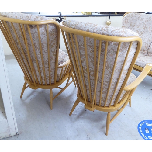 68 - A pair of Ercol high back blonde beech and elm framed, spindled open arm chairs with loose fabric co... 