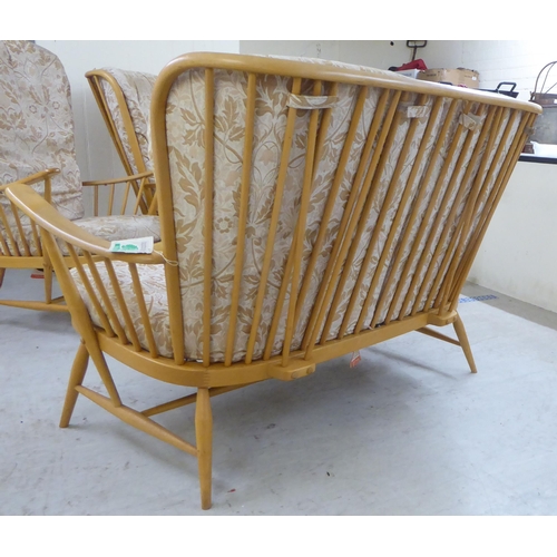 69 - An Ercol blonde beech and elm framed settee with a spindled, level back and open arms, raised on ell... 