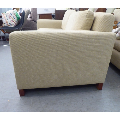 72 - A modern two person settee, upholstered in oatmeal coloured fabric with a level back and arms, raise... 