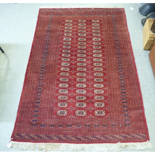 84 - A Bokhara rug, decorated with three columns of twenty guls, on a red ground  50