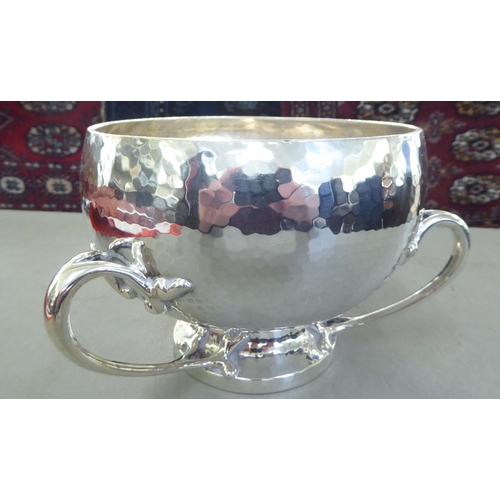 63 - A post modern period spot-hammered silver rose bowl of bulbous form with an inverted rim and three a... 