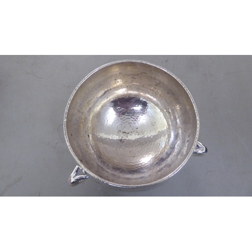 63 - A post modern period spot-hammered silver rose bowl of bulbous form with an inverted rim and three a... 