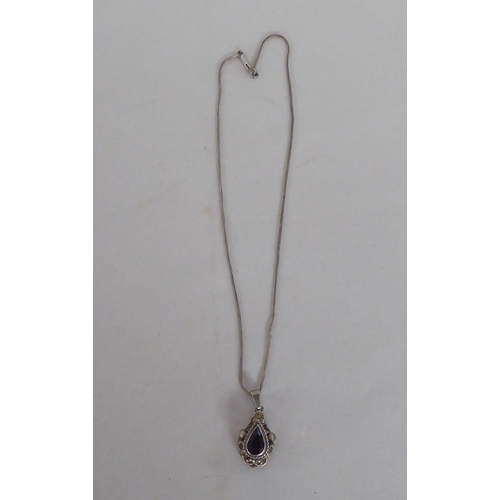 103 - A white metal pendant, set with a teardrop cut garnet, on a white metal chain  stamped 800