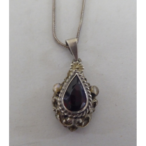 103 - A white metal pendant, set with a teardrop cut garnet, on a white metal chain  stamped 800