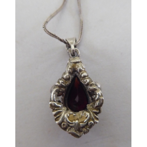 103 - A white metal pendant, set with a teardrop cut garnet, on a white metal chain  stamped 800