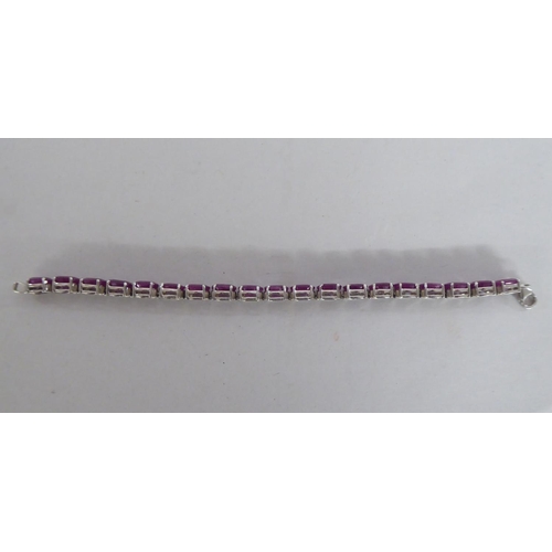 106 - A white metal bracelet, set with rivetted oval cut rubies  stamped 925