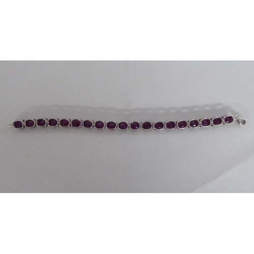 106 - A white metal bracelet, set with rivetted oval cut rubies  stamped 925