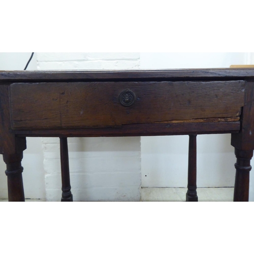 107 - A George III oak single drawer side table, raised on turned and block legs  25