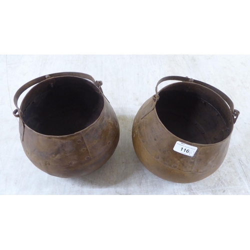 116 - A pair of rivetted cast metal hanging cooking pots