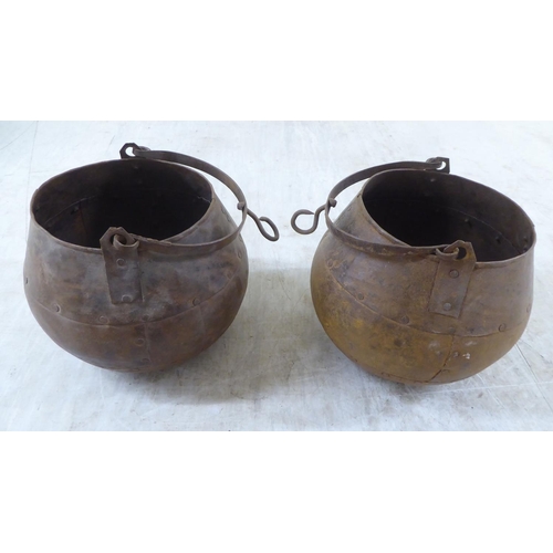 116 - A pair of rivetted cast metal hanging cooking pots