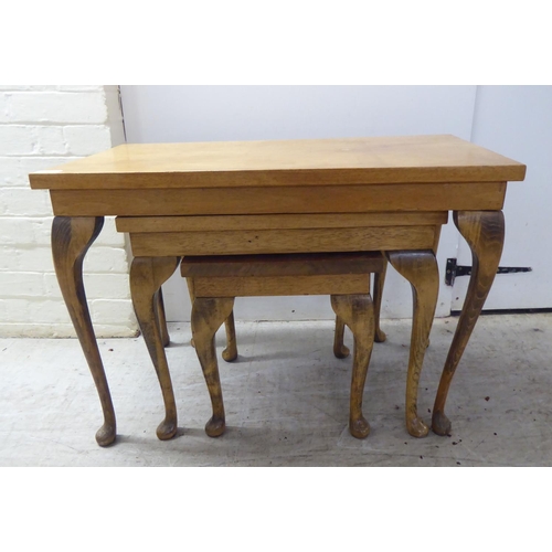 172 - A nesting set of three mid 20thC beech and mahogany occasional tables, raised on slender legs and pa... 