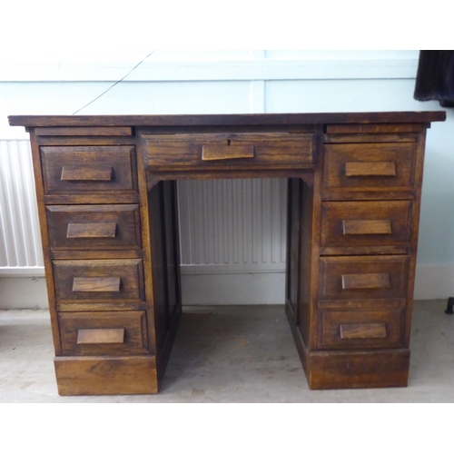 208 - A 1930s oak veneered one piece, nine drawer twin pedestal desk, on a plinth  30