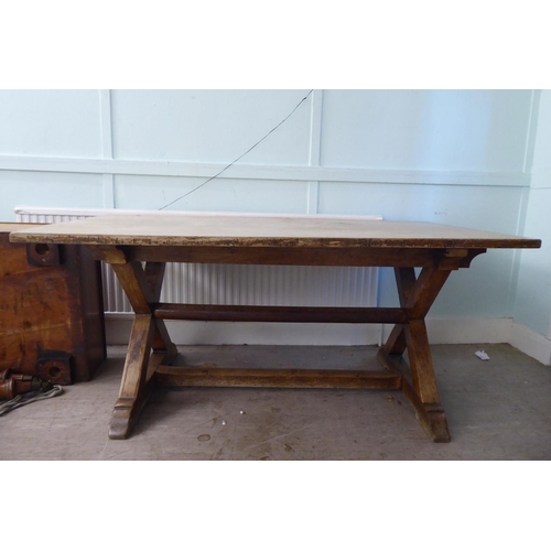 212 - A late 19thC oak refectory table, the planked top over a pair of crossover supports and platform fee... 