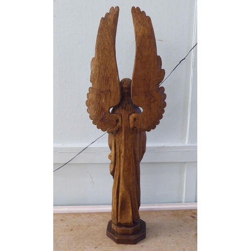 241 - A 20thC carved oak figure, a standing angel with outspread wings, on an octagonal plinth  29