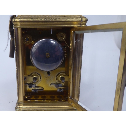 268 - An early 20thC (probably French) lacquered and ornately engraved brass and glazed carriage timepiece... 