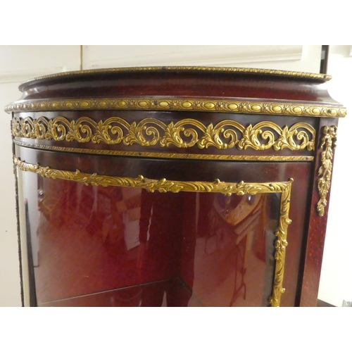 277 - A 20thC reproduction of an 18thC European inspired stained beech corner vitrine with gilt metal moun... 