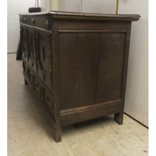 280 - A late 18thC oak coffer with straight sides and a hinged lid, a panelled front and two drawers, rais... 