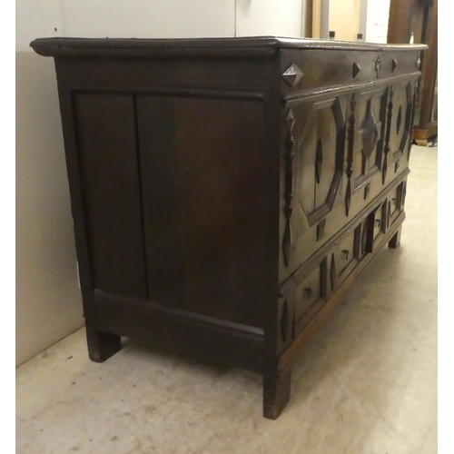 280 - A late 18thC oak coffer with straight sides and a hinged lid, a panelled front and two drawers, rais... 