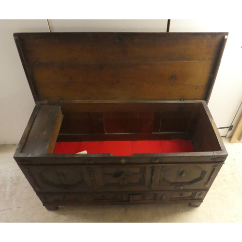 280 - A late 18thC oak coffer with straight sides and a hinged lid, a panelled front and two drawers, rais... 