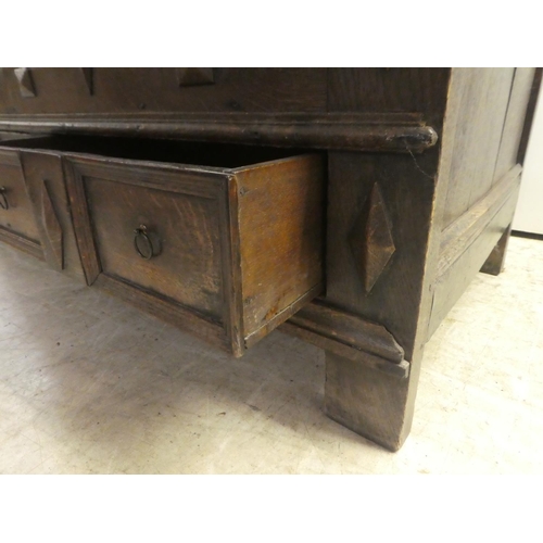 280 - A late 18thC oak coffer with straight sides and a hinged lid, a panelled front and two drawers, rais... 