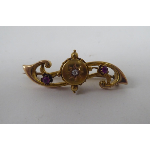 292 - A 15ct gold brooch, set with a central diamond, flanked by two coloured stones 