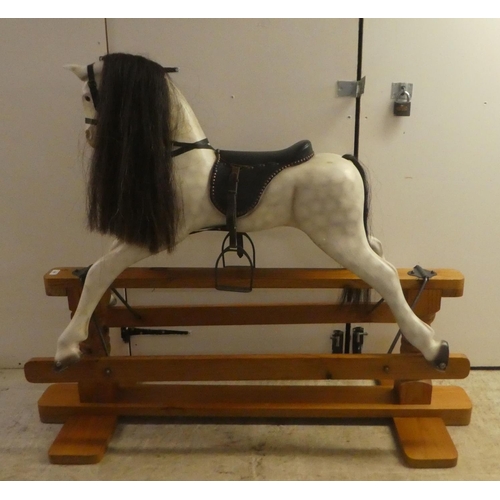 329 - A modern hardwood dapple grey painted rocking horse with a leatherette saddle, raised on a pillar ba... 