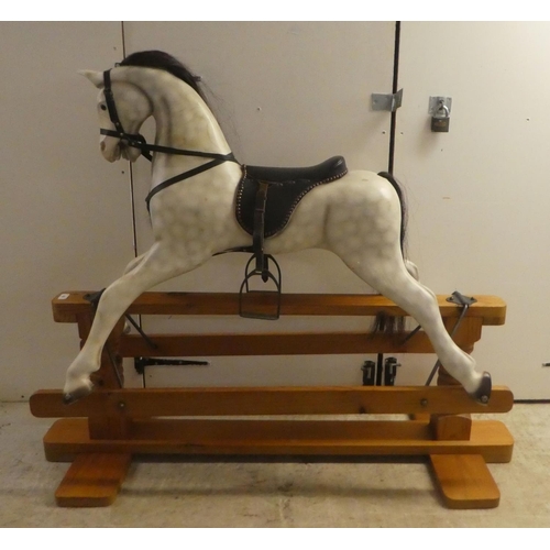 329 - A modern hardwood dapple grey painted rocking horse with a leatherette saddle, raised on a pillar ba... 