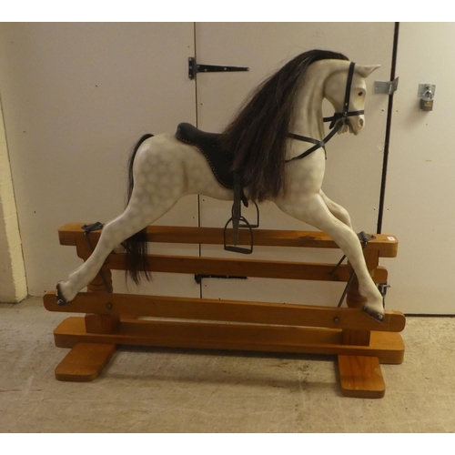 329 - A modern hardwood dapple grey painted rocking horse with a leatherette saddle, raised on a pillar ba... 