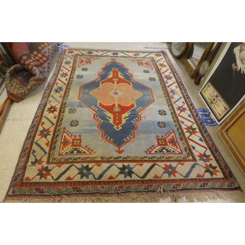 79 - An Afghan Kazak rug, decorated with a central motif, surrounded by stylised designs, on a multi-colo... 