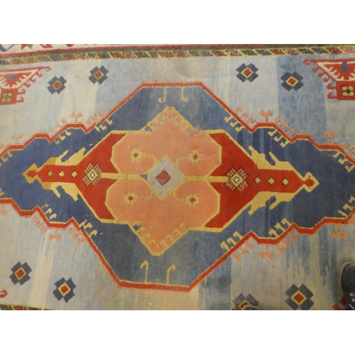 79 - An Afghan Kazak rug, decorated with a central motif, surrounded by stylised designs, on a multi-colo... 